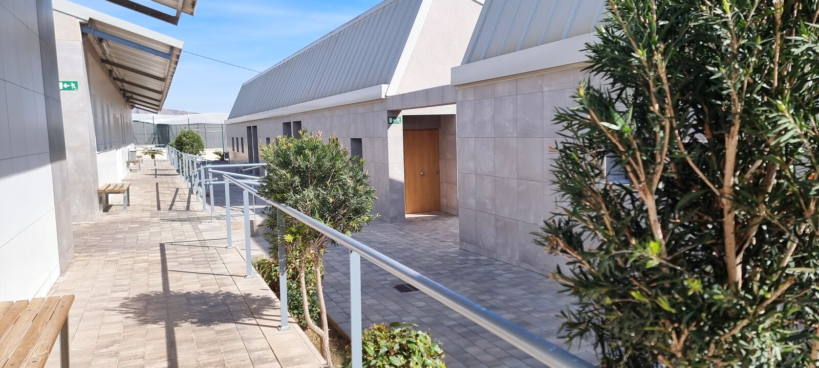 Pasillo exterior de aularios con jardineras